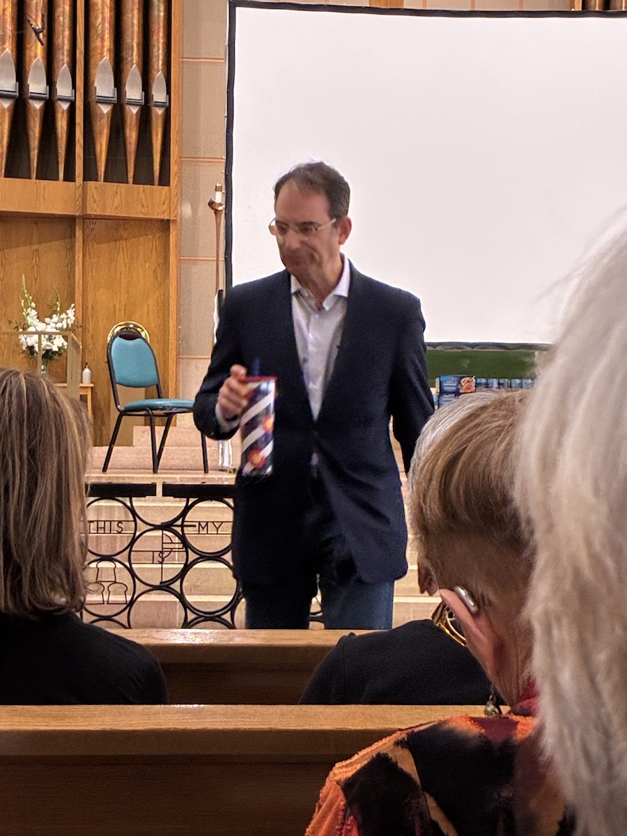 Phil Weiser returns to his seat after speaking.