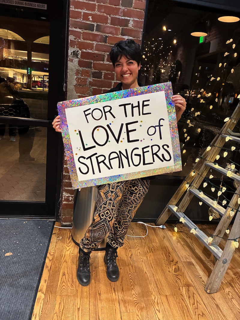 Cori Wong stands inside the entryway to the venue holding the hand-made sign that was recently to be attached to the door facing the outside.